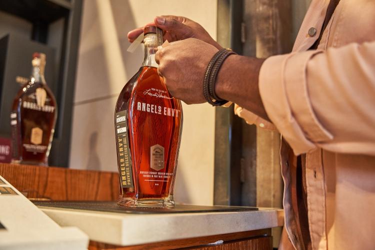 Man placing a label over the cork of the Angel's Envy bottle.