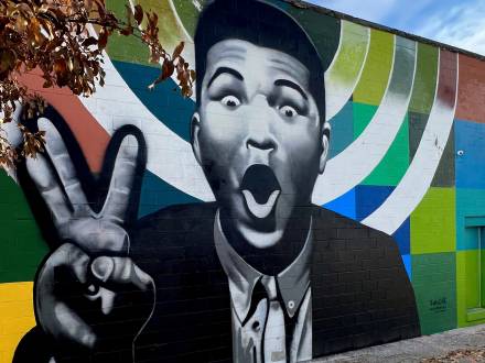 black and white mural of Muhammad Ali with a colorful background on a building in Louisville