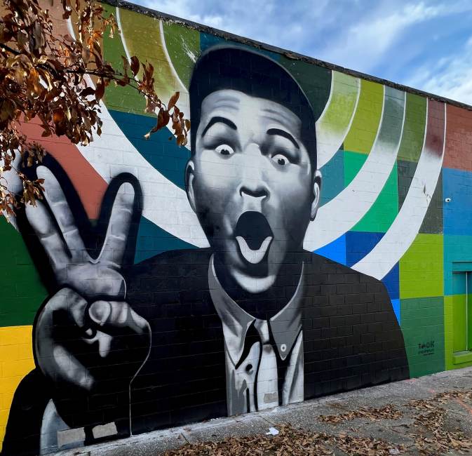 black and white mural of Muhammad Ali with a colorful background on a building in Louisville