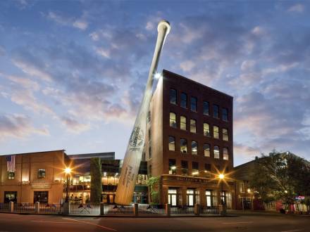 Exterior photo of Louisville Slugger Museum & Factory showing the giant baseball bat out front leaning against the building.