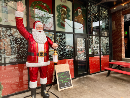 A large Santa statue waves outside holiday pop-up bar Miracle on Market decorated with snowflakes and Christmas-themed art.