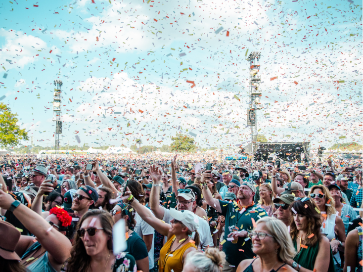 Crowds cheer under a shower of colorful confetti at Louisville’s Bourbon & Beyond music festival on a sunny day.