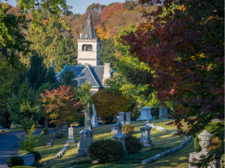 Cave Hill Cemetery in Louisville with historic monuments, colorful autumn trees, and a stone chapel tower in the background.