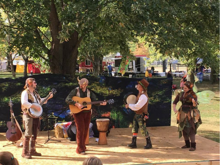 Four people dressed as woodland fairies and creatures are playing musical instruments at Louisville Pagan Roots Festival.